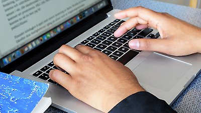 Ett par händer som skriver på en laptop